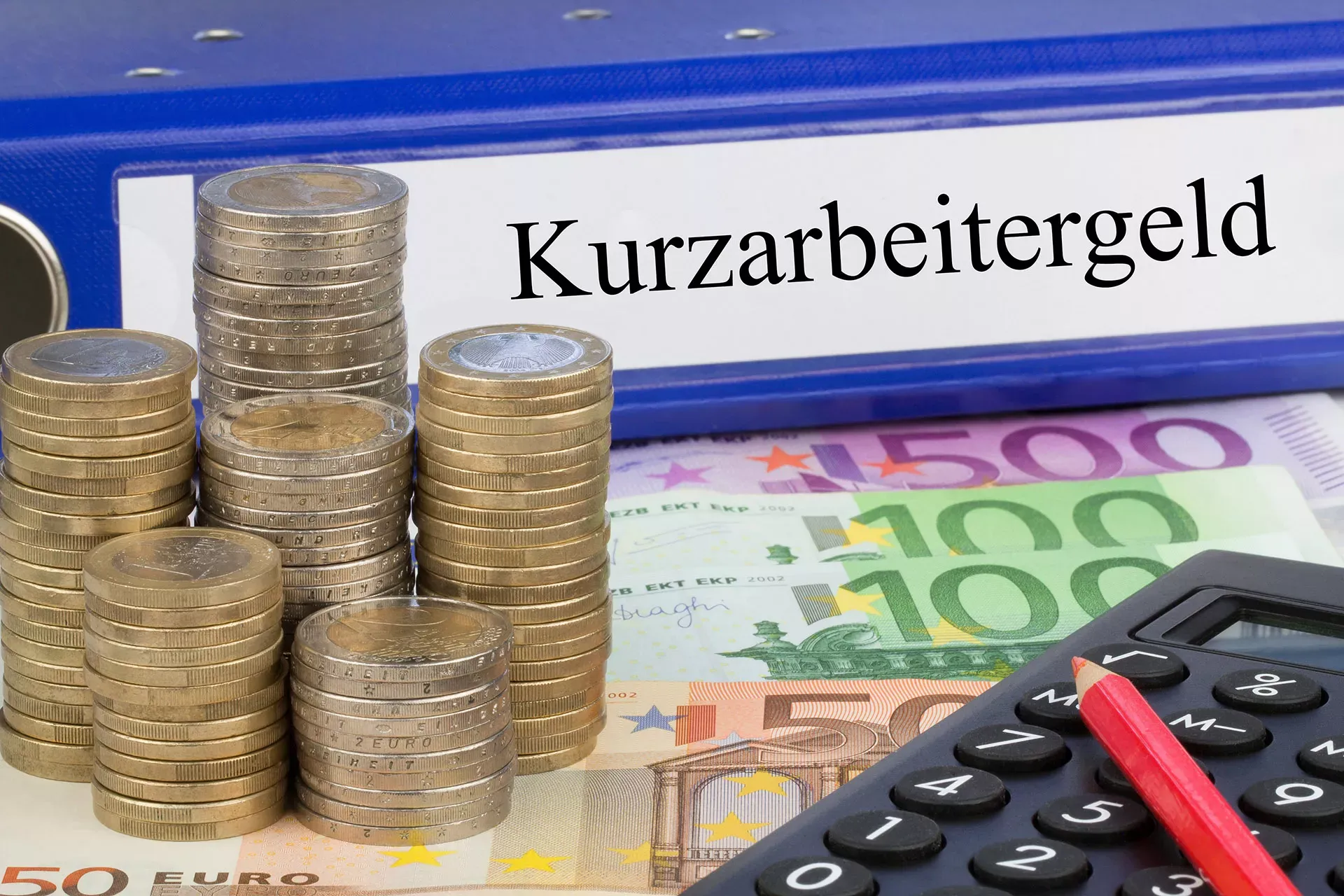 Ordner Kurzarbeitergeld mit Münzen, Geldscheinen, Taschenrechner und einem Stift.