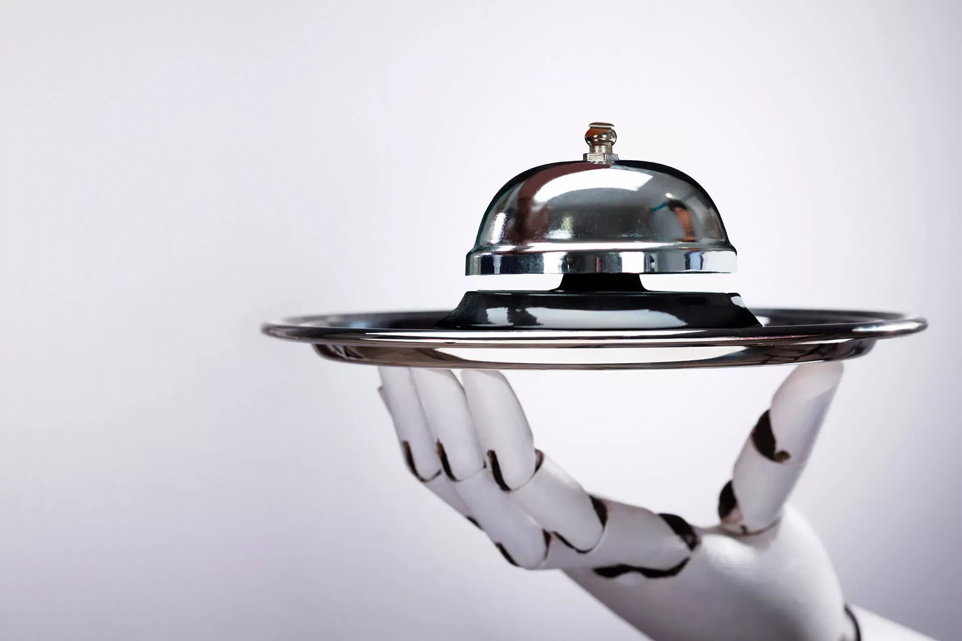 Roboterhand hält ein Tablett mit einer Service-Klingel.