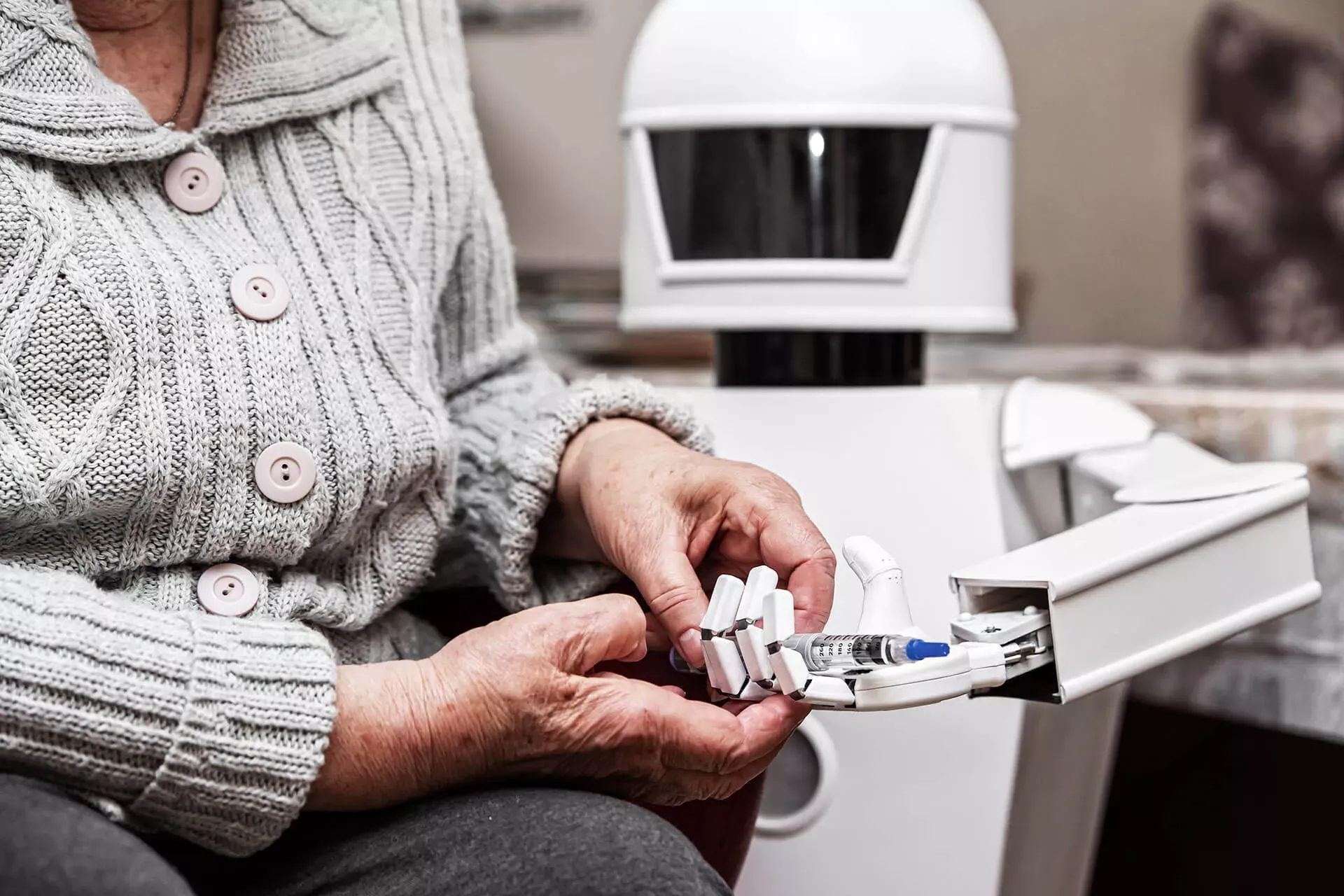 Roboter reicht einer Seniorin eine Spritze an. Roboter reicht einer Seniorin eine Spritze an.