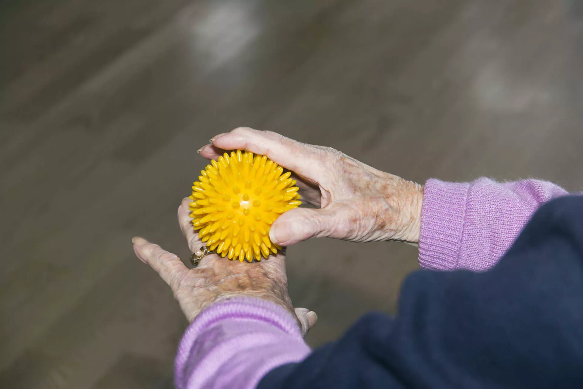 Hände einer alten Frau machen Übungen mit einem Massageball. Bild: IMAGO / CHROMORANGE /imago stock&people
