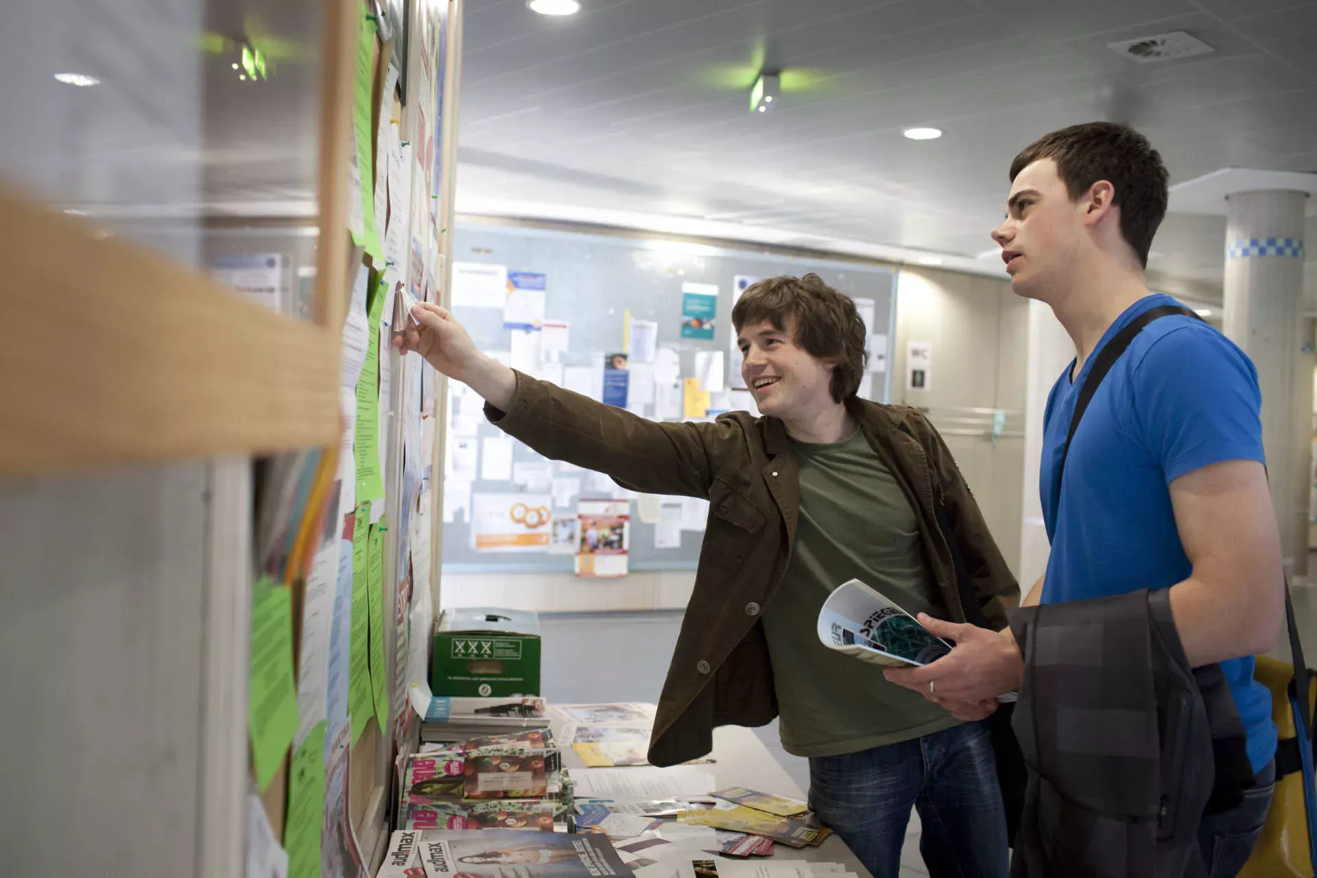 Studenten auf Jobsuche stehen vor einem schwarzen Brett mit Aushängen an der Uni. Bild: IMAGO / photothek / Ute Grabowsky