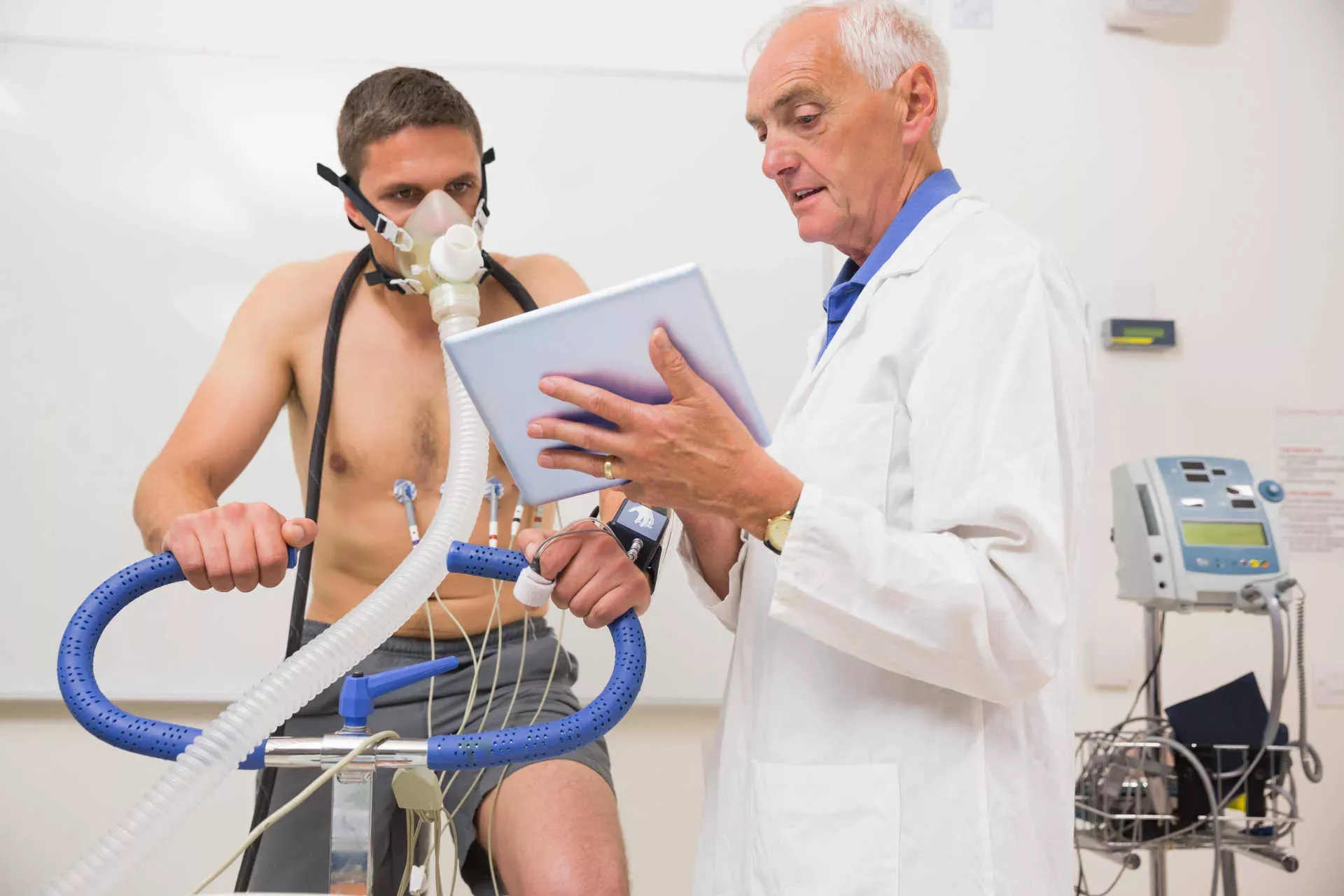 Arzt zeigt einem Mann Messdaten auf einem Tablet, der auf einem Cardiorad einen Fitnesstest mit Atemmaske macht. Bild: IMAGO / Panthermedia / WavebreakmediaMicro Arzt zeigt einem Mann Messdaten auf einem Tablet, der auf einem Cardiorad einen Fitnesstest mit Atemmaske macht. Bild: IMAGO / Panthermedia / WavebreakmediaMicro