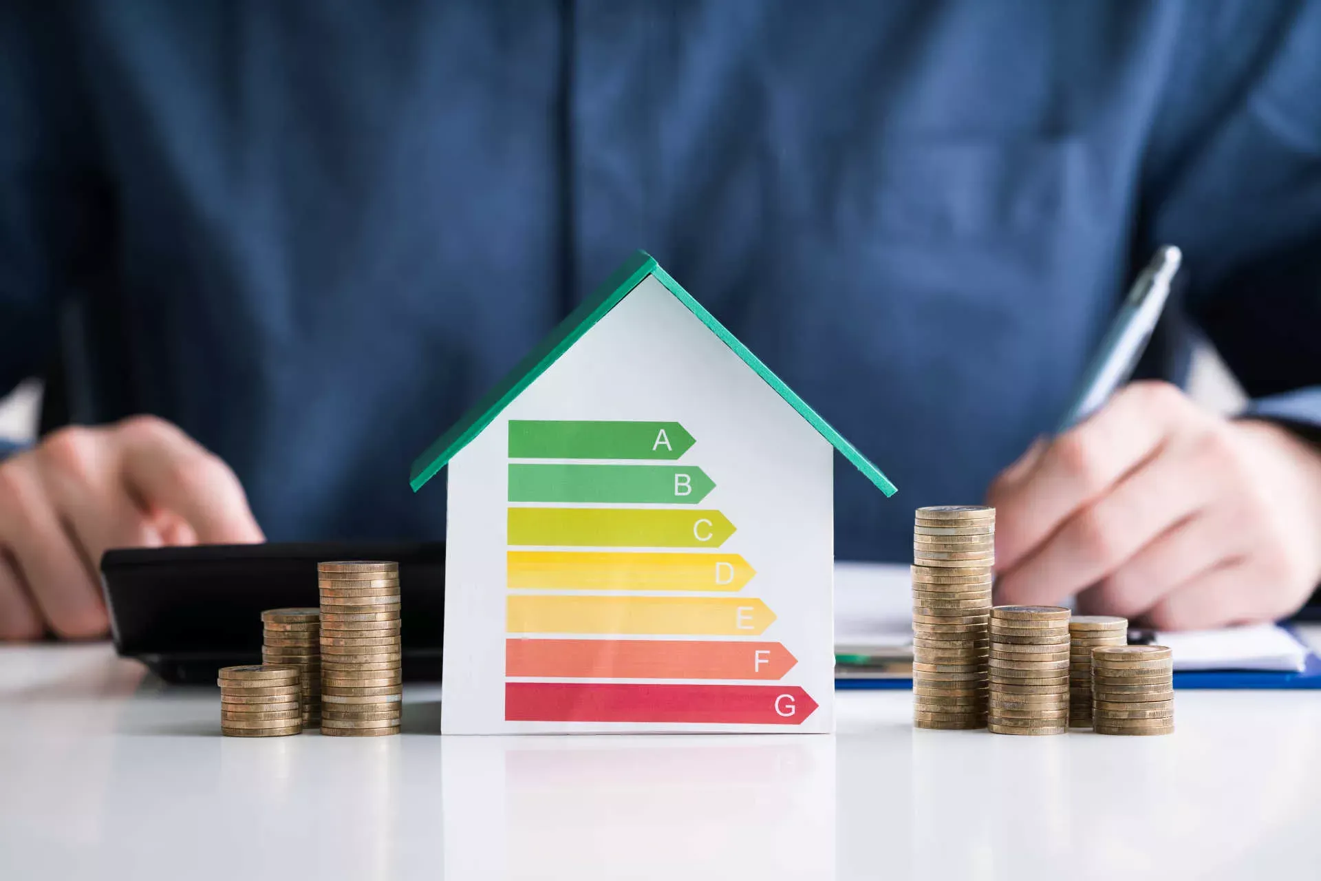 Mann rechnet mit Taschenrechner und füllt Antrag aus, im Vordergrund Hausmodell energieeffizient und Stapel von Münzen. Bild: IMAGO / Panthermedia / Andrey Popov Mann rechnet mit Taschenrechner und füllt Antrag aus, im Vordergrund Hausmodell energieeffizient und Stapel von Münzen. Bild: IMAGO / Panthermedia / Andrey Popov