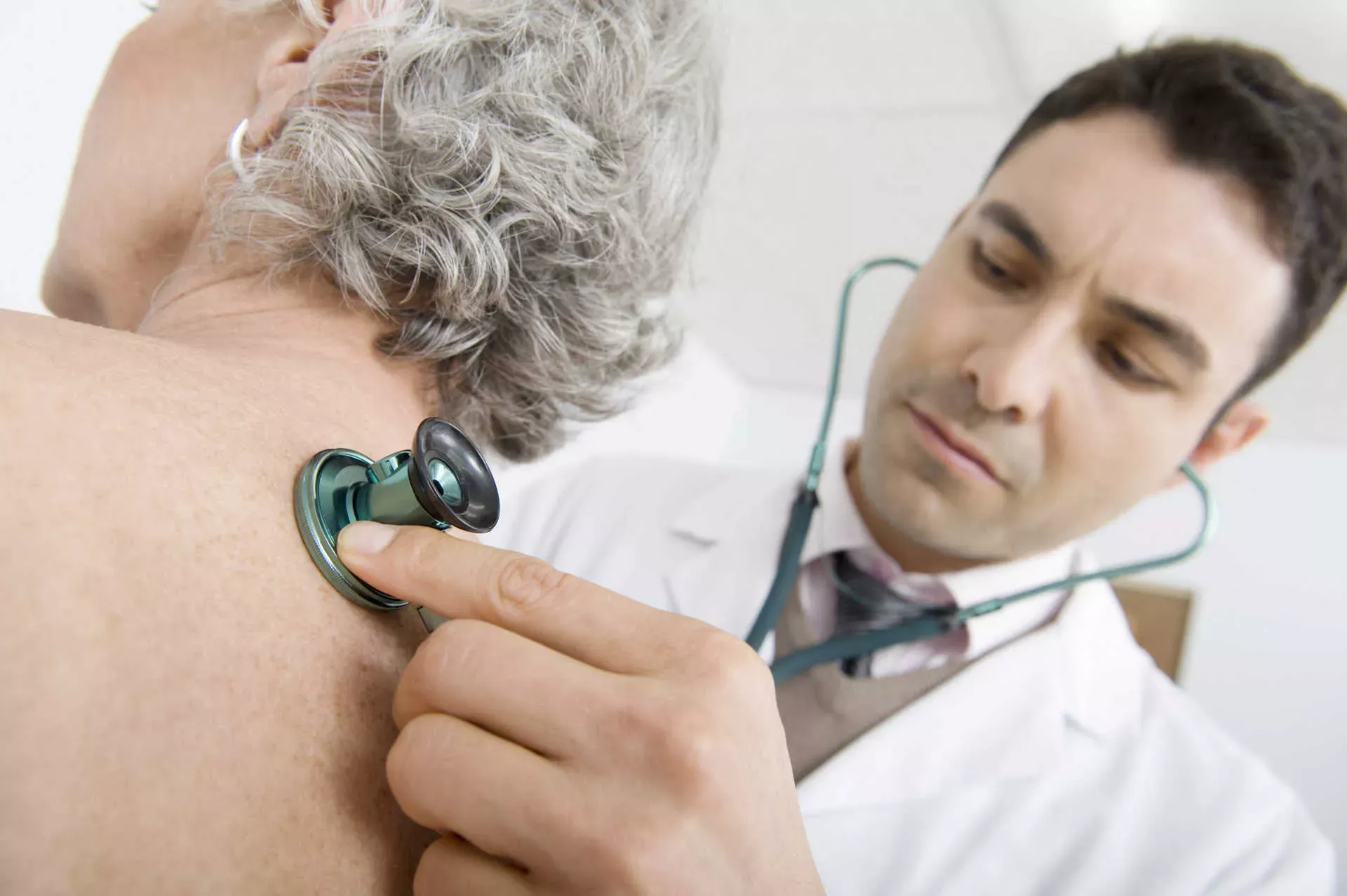 Arzt hört Rücken einer ältere Patientin mit Stethoskop ab. Bild: IMAGO / YAY Images / moodboard