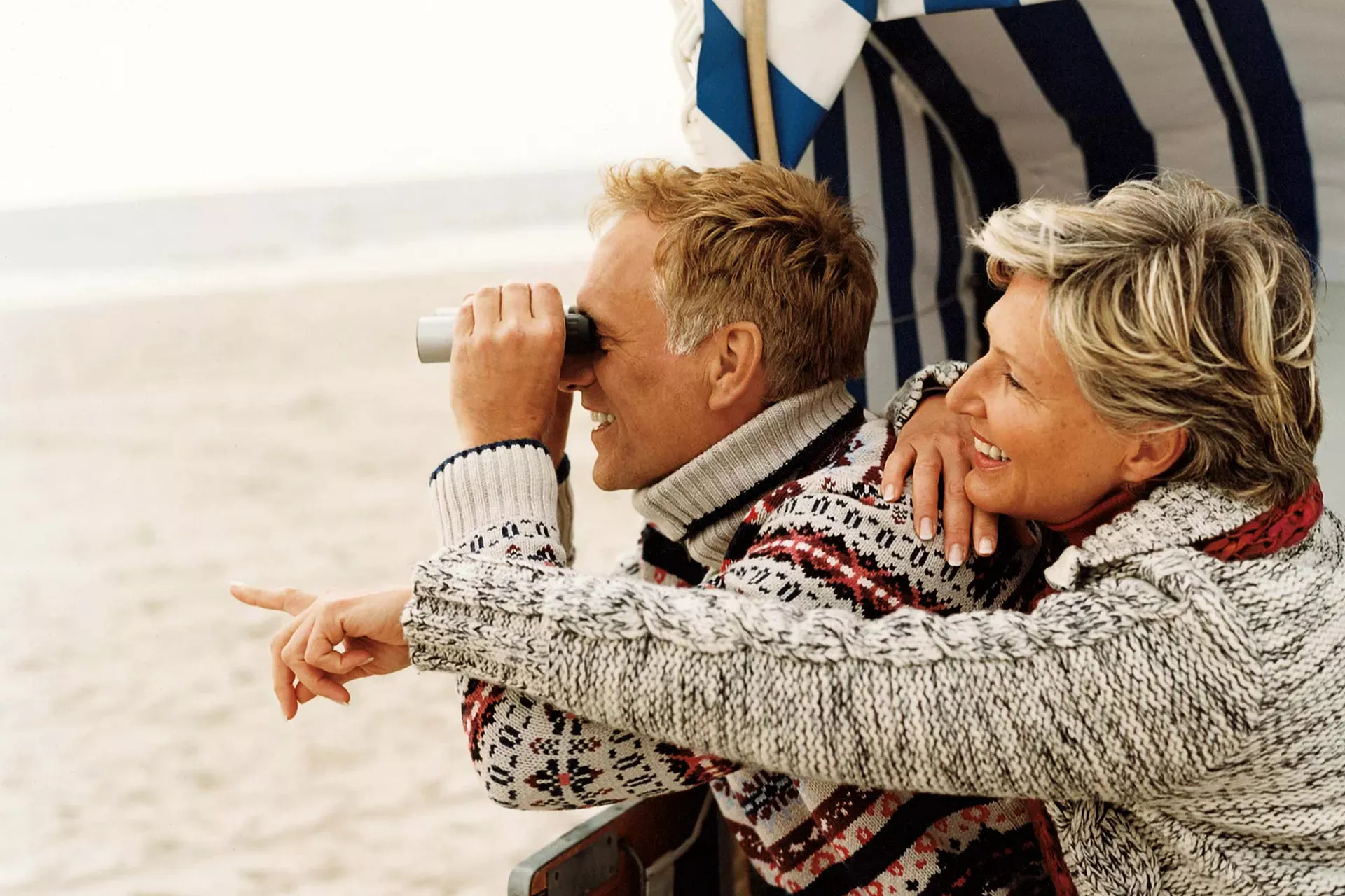 Älteres Paar sitzt in herbstlicher Kleidung in einem Strandkorb, Mann schaut durch ein Fernglas. Älteres Paar sitzt in herbstlicher Kleidung in einem Strandkorb, Mann schaut durch ein Fernglas.