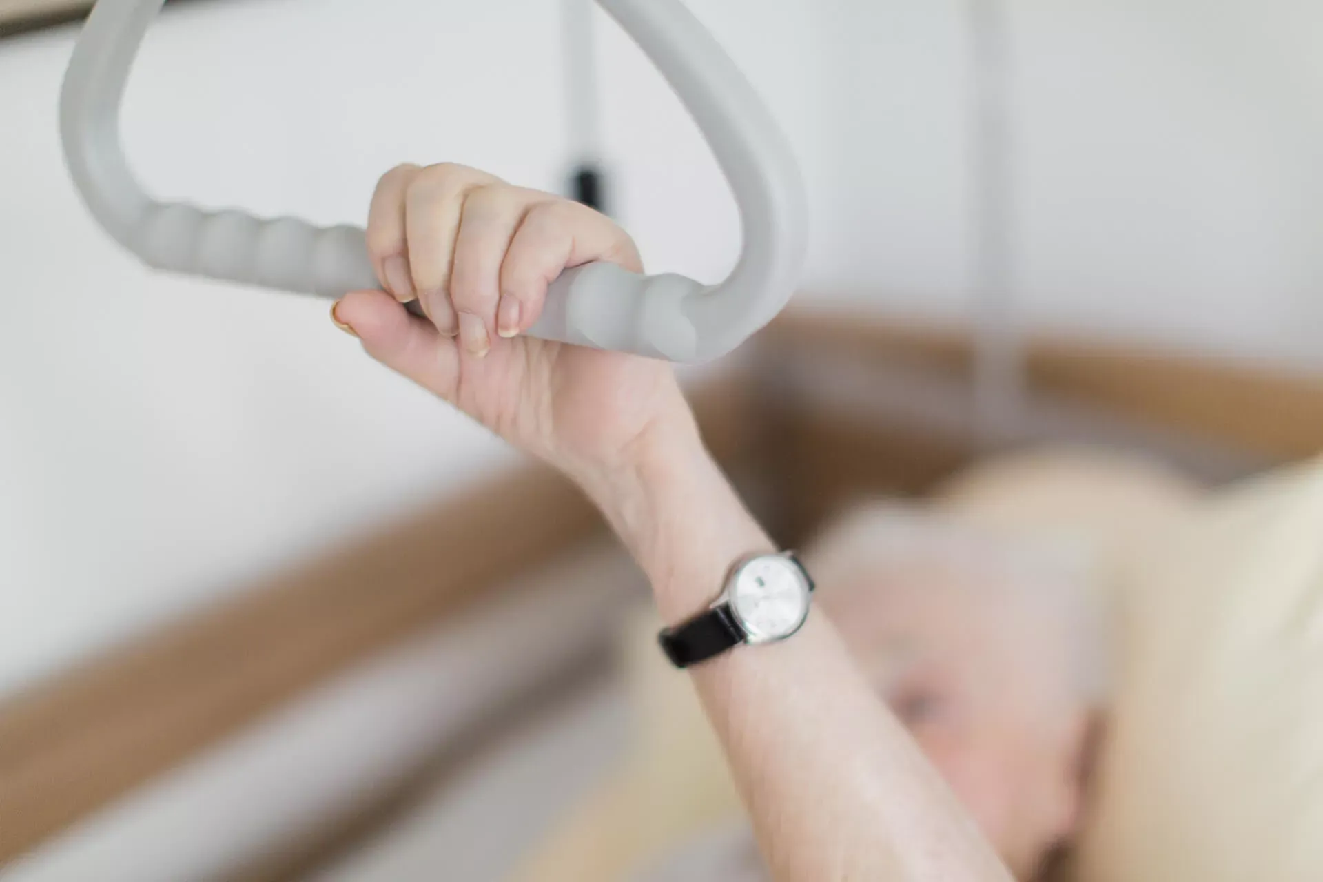 Hand eines Pflegebedürftigen greift Haltegriff am Bett.