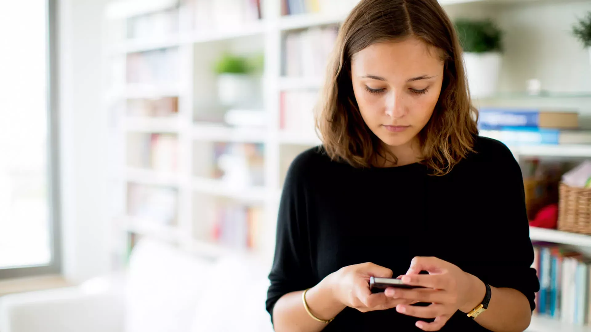 Mädchen im Teenageralter steht im Wohnzimmer und tippt auf ihrem Smartphone. – Bildnachweis: wdv.de © Szekely.Oana Mädchen im Teenageralter steht im Wohnzimmer und tippt auf ihrem Smartphone. – Bildnachweis: wdv.de © Szekely.Oana