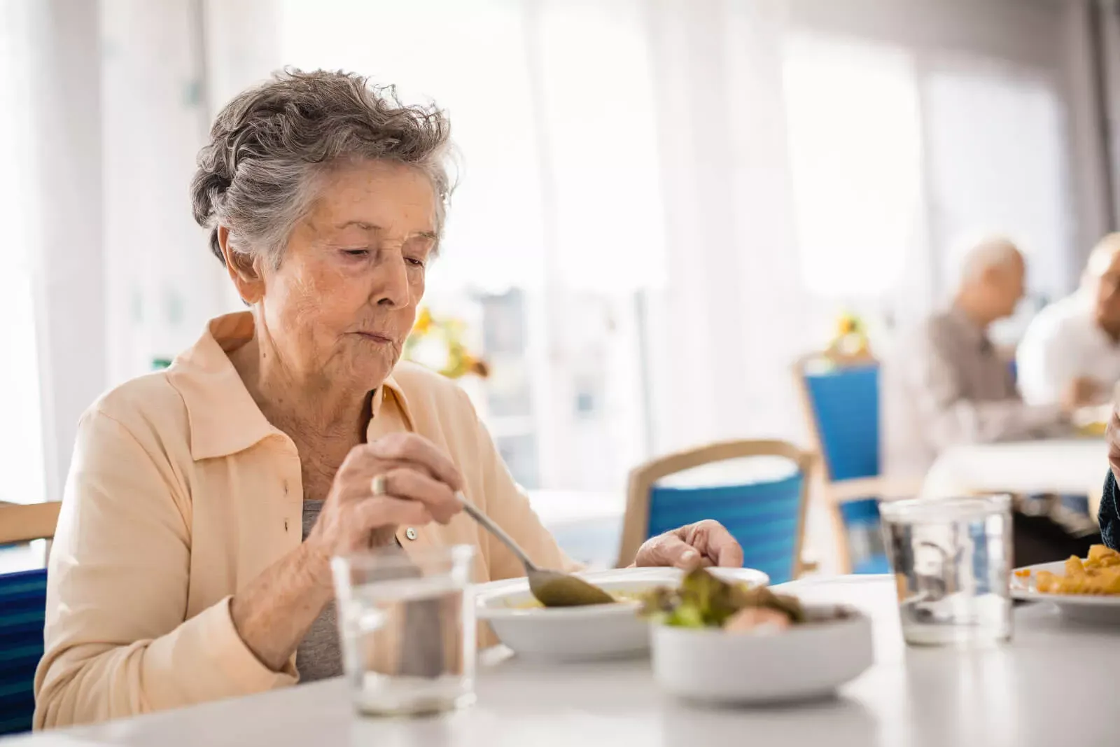 Alte Frau sitzt in einem Speisesaal an einem Tisch beim Essen. Alte Frau sitzt in einem Speisesaal an einem Tisch beim Essen.