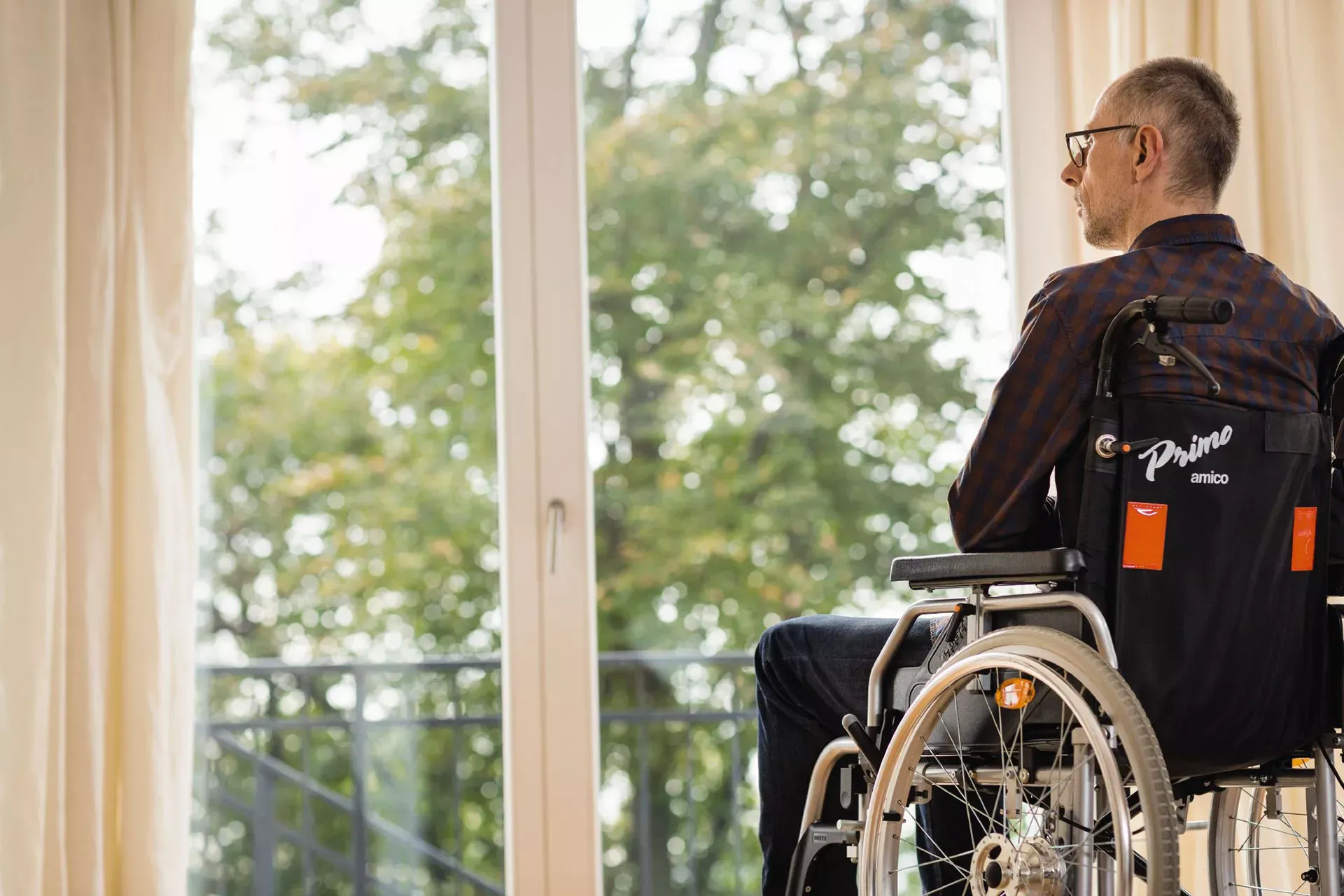 Mann mit Behinderung sitzt im Rollstuhl am Fenster. Mann mit Behinderung sitzt im Rollstuhl am Fenster.