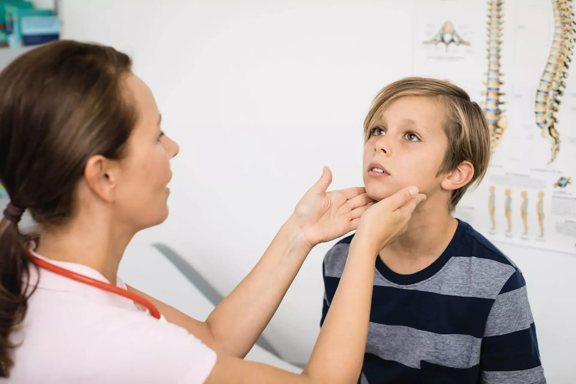 Kinderärztin tastet Lymphknoten am Hals eines Jungen ab.